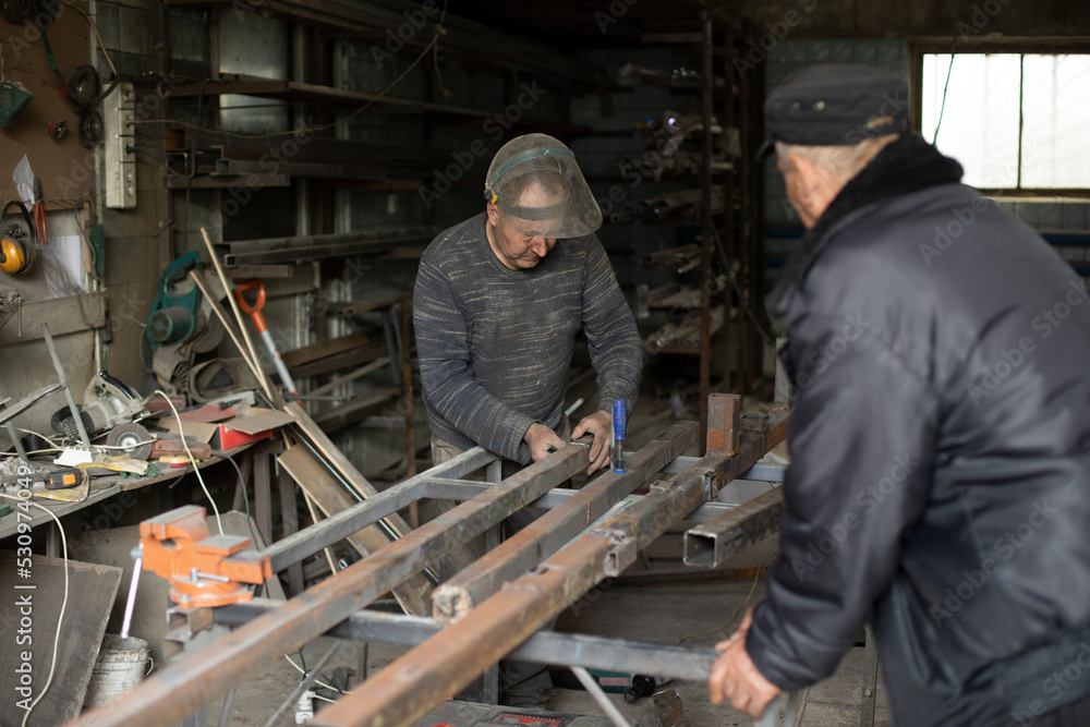 Welder holds metal. People in metal workshop. Work in garage. Welder holds metal. People in metal workshop. Work in garage.