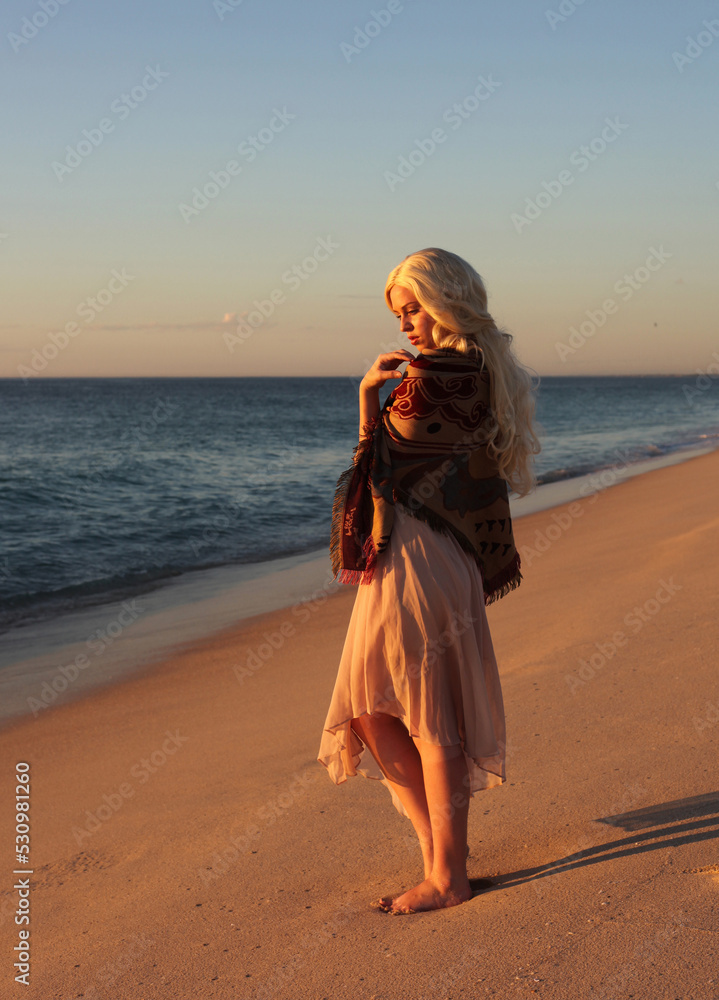 full length portrait of beautiful young woman with long hair wearing flowing dress, standing pose walking away from the camera. ocean beach background with sunset lighting. full length portrait of beautiful young woman with long hair wearing flowing dress, standing pose walking away from the camera. ocean beach background with sunset lighting.