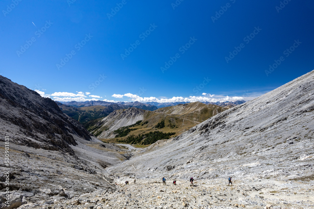 Hikers walk on the path that leads to Mount Chaberton, peak in the French Alps in the group known as the Massif des Cerces in the département of Hautes-Alpes