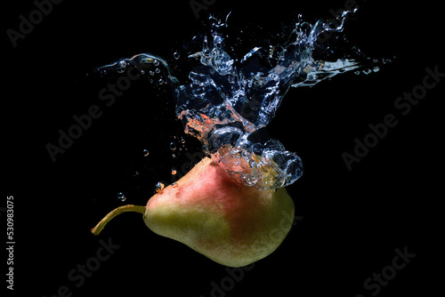 Pear dropped in water with splashes on black