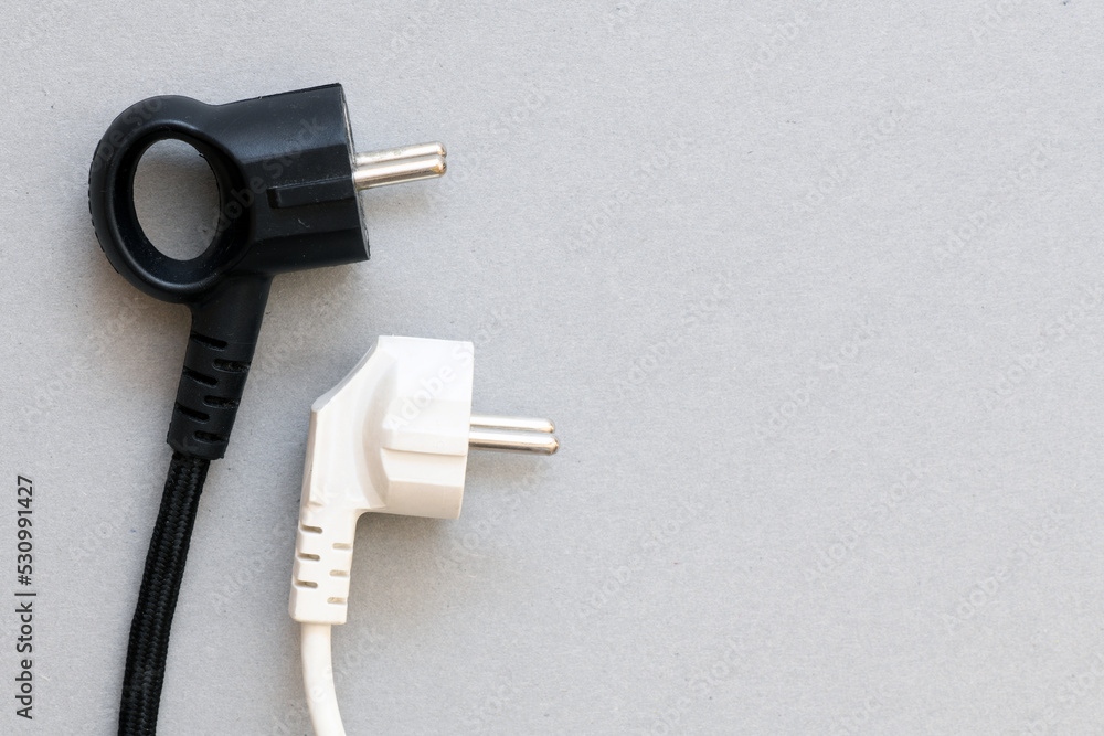 Black and white electric plug on a gray background. Concept for business, rising costs of electric current. Black and white electric plug on a gray background. Concept for business, rising costs of electric current.