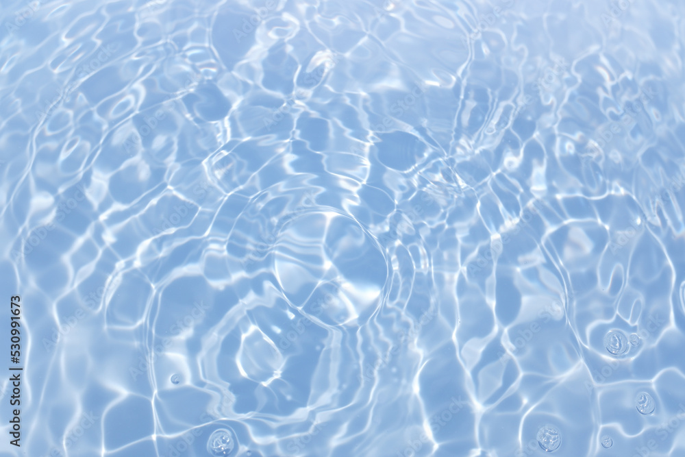 Bluewater waves on the surface ripples blurred. Defocus blurred transparent blue colored clear calm water surface texture with splash and bubbles. Water waves with shining pattern texture background. Bluewater waves on the surface ripples blurred. Defocus blurred transparent blue colored clear calm water surface texture with splash and bubbles. Water waves with shining pattern texture background.