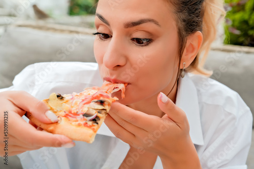 beautiful girl eats pizza in a street cafe. girl shows different emotions
