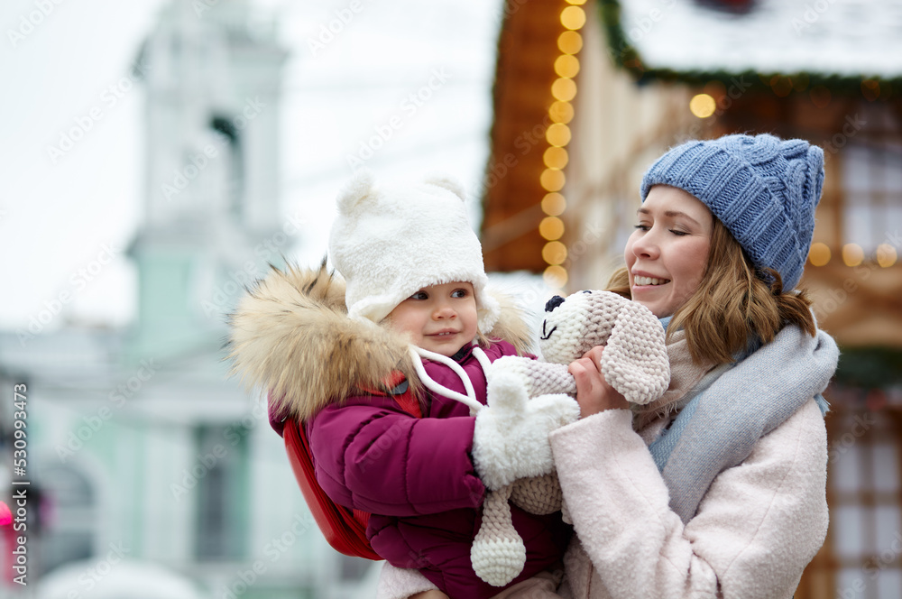 Mother and daughter are walking around the city on Christmas and New Year holidays. Parent and little child having fun outdoors Mother and daughter are walking around the city on Christmas and New Year holidays. Parent and little child having fun outdoors
