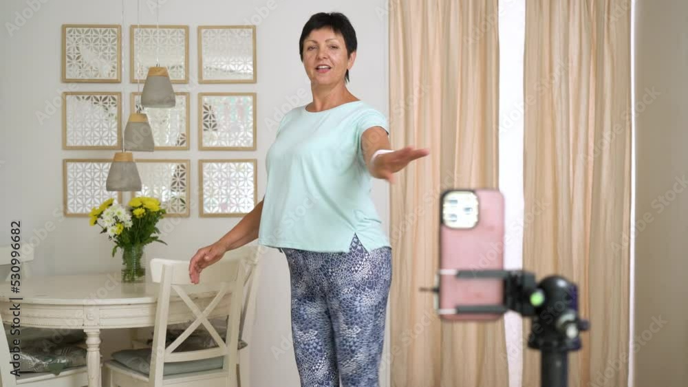Mature woman recording trendy dance moves for social media account at home. Woman 50-60 years old shooting short video on smartphone. Concept social media, stories, and TikTok trendy dance. Mature woman recording trendy dance moves for social media account at home. Woman 50-60 years old shooting short video on smartphone. Concept social media, stories, and TikTok trendy dance.