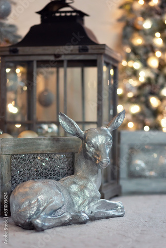 Silver figurine of a deer on the background of a Christmas garland.