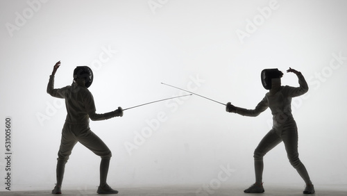 Fotografía Side view of two young female swordswoman with crossed rapiers