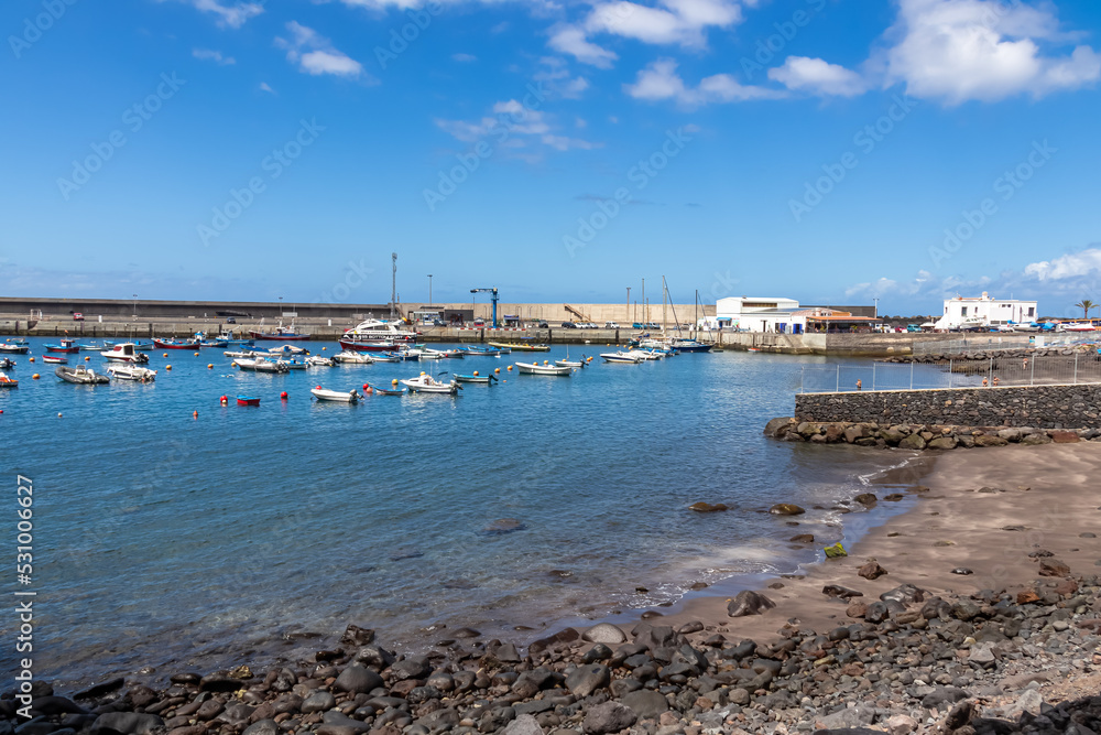Scenic view on the small port of Vueltas seen from Playa de Vueltas in Valle Gran Rey on La Gomera, Canary Islands, Spain, Europe. Small boats are floating in the blue lagoon bay on a sunny summer day