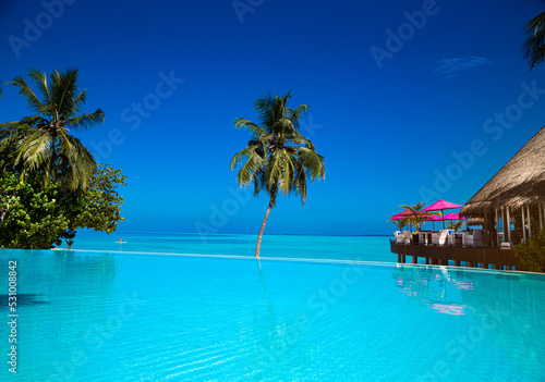 Fototapeta Naklejka Na Ścianę i Meble -  Landscape on Maldives island, luxury water villas resort with pool. Beautiful sky and ocean and beach with palms background for summer vacation holiday and travel concept. Luxury travel.