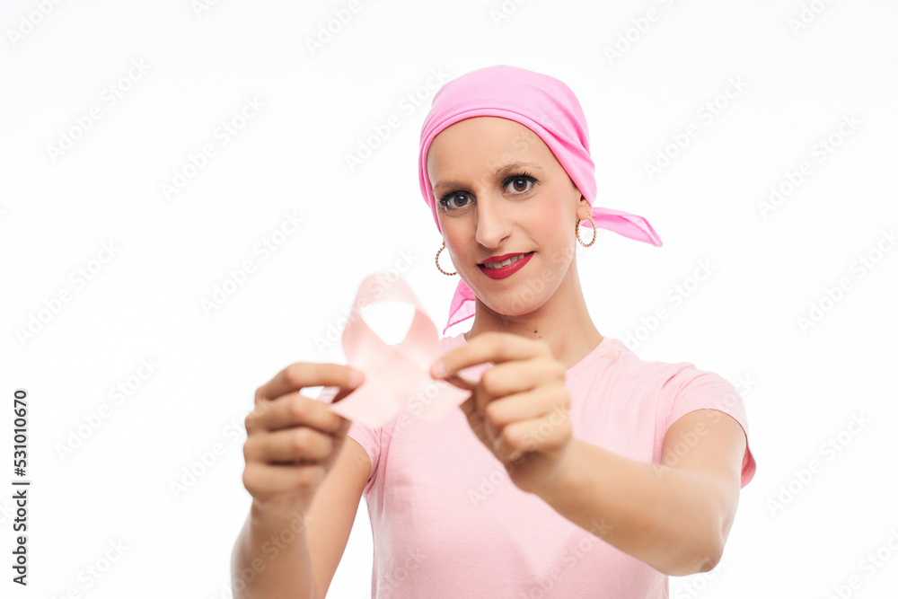 Smiling woman with cancer with pink headscarf holds ribbon bow in hand. Cancer awareness Smiling woman with cancer with pink headscarf holds ribbon bow in hand. Cancer awareness