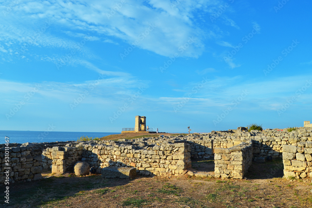 An old stone building in Chersonesos with a view of the bell and the Black Sea under a blue sky