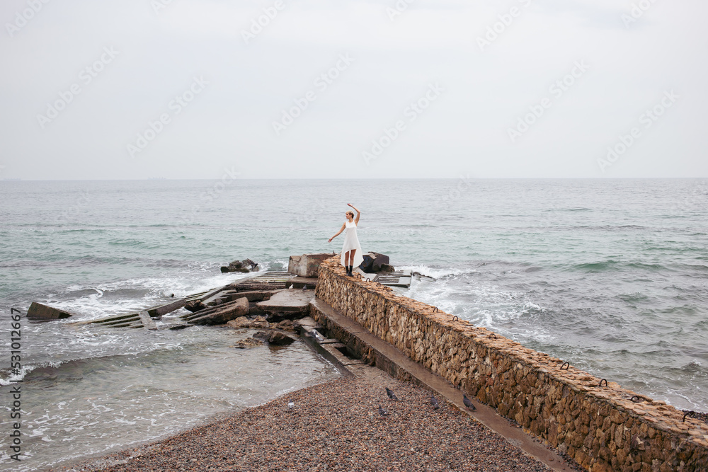 back view of woman wearing white dress near sea in autumn