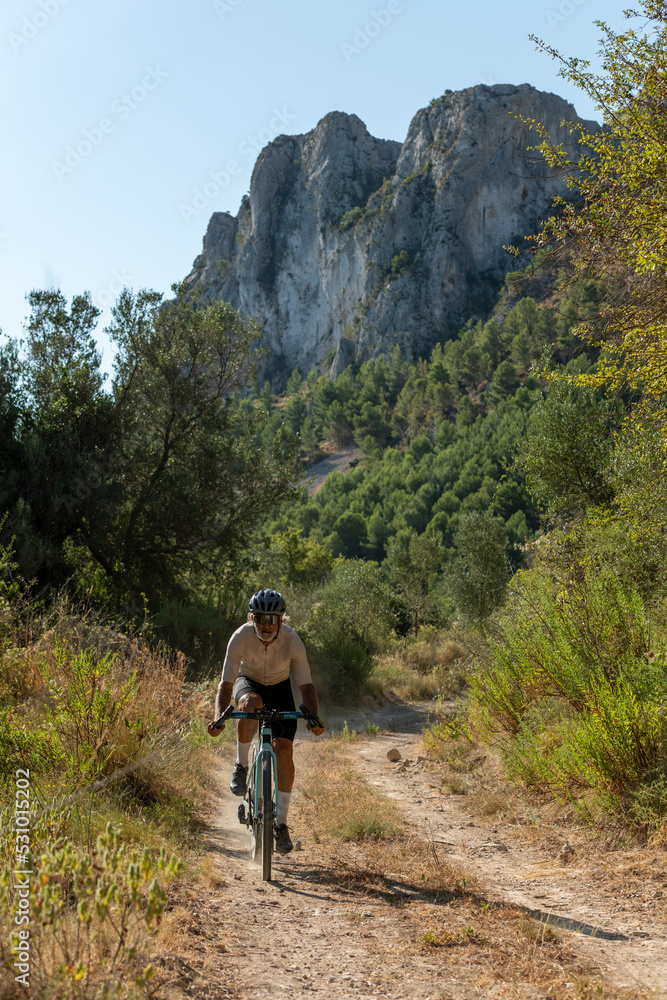 A male cyclist in a gravel road bicycle ride in the  mountains of Costa Blanca, Alicante, Spain