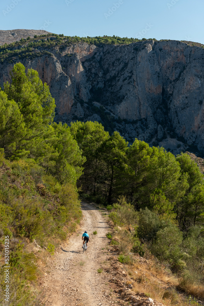 A male cyclist in a gravel road bicycle ride in the mountains of Costa Blanca, Alicante, Spain