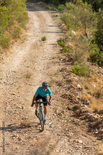 A male cyclist in a gravel road bicycle ride in the mountains of Costa Blanca, Alicante, Spain