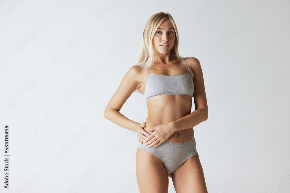 Young pretty slim 35 years old woman in cotton inner wear isolated over gray studio background. Wellness, wellbeing, fitness, diet, natural beauty of female body Young pretty slim 35 years old woman in cotton inner wear isolated over gray studio background. Wellness, wellbeing, fitness, diet, natural beauty of female body