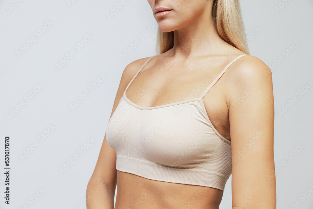 Cropped image of slender female body, breast and shoulders isolated over grey studio background. Cancer prevention. Concept of beauty, fashion, body care