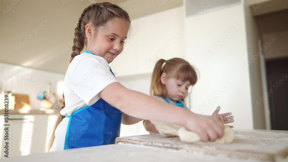 children making dough in the kitchen. two little girls cook in the kitchen knead dough and fun flour indoors. happy family kid dream concept. children play cooking dough together at home children making dough in the kitchen. two little girls cook in the kitchen knead dough and fun flour indoors. happy family kid dream concept. children play cooking dough together at home