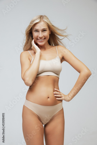 Young pretty slim 35 years old woman in cotton inner wear isolated over gray studio background. Wellness, wellbeing, fitness, diet, natural beauty of female body