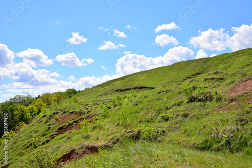 green hill with blue sky and white clouds on background