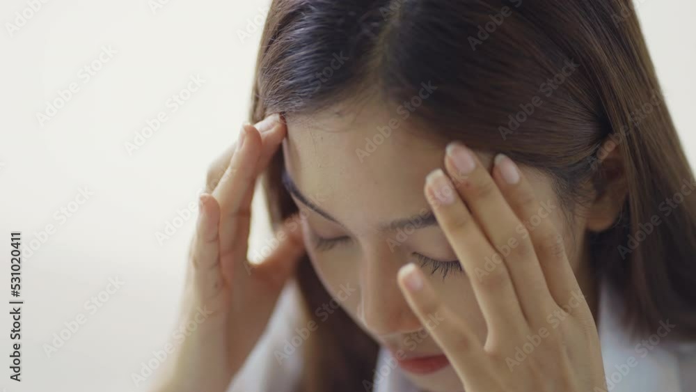 Tired Thai student girl at university in office holding his head on hands feel headache. Asian woman feeling stress from work in the office. Tired Thai student girl at university in office holding his head on hands feel headache. Asian woman feeling stress from work in the office.