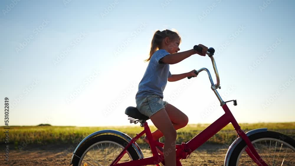 kid bike riding on a park. kid girl rides a bike in nature in the park on the road. happy family kid dream concept. daughter plays a bike rides lifestyle on a sandy road kid bike riding on a park. kid girl rides a bike in nature in the park on the road. happy family kid dream concept. daughter plays a bike rides lifestyle on a sandy road