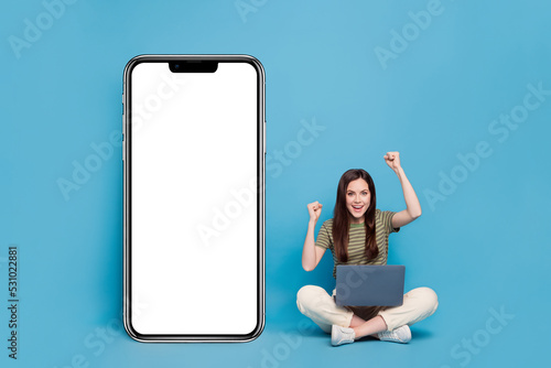 Full body photo of hooray young lady sit hold laptop near promo wear casual cloth isolated on blue background © deagreez