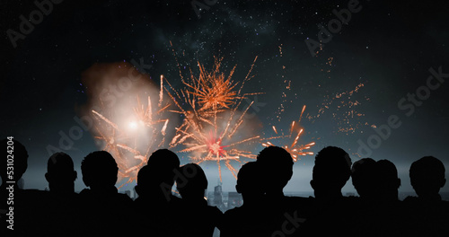 Image of silhouettes of people and cityscape over fireworks
