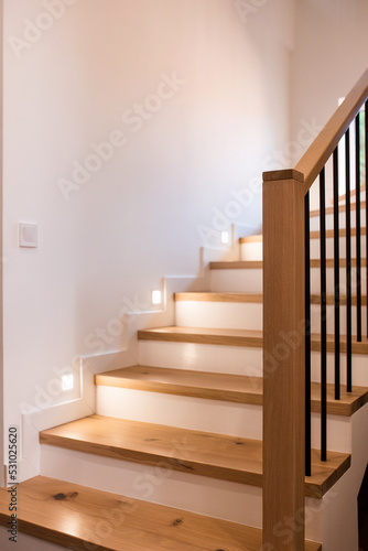 Wood staircase inside contemporary white modern house.