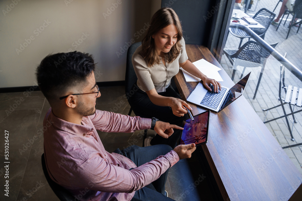 Fototapeta premium Portrait of woman and man pointing to tablet relaxing in coffee bar.