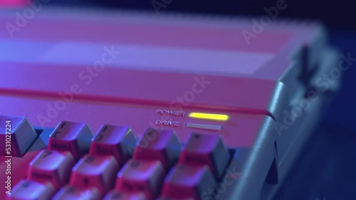 Closeup of a hand inserting a floppy into a microcomputer and loading the disk in a dark atmosphere