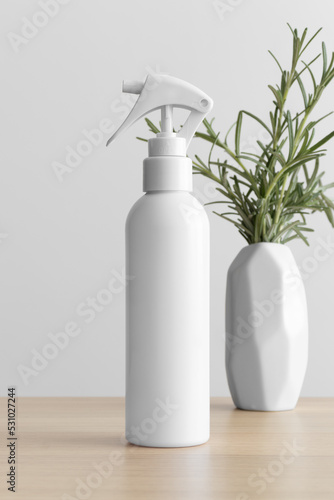 White cosmetic trigger sprayer bottle mockup with a rosemary on the wooden table. © Snoflinga