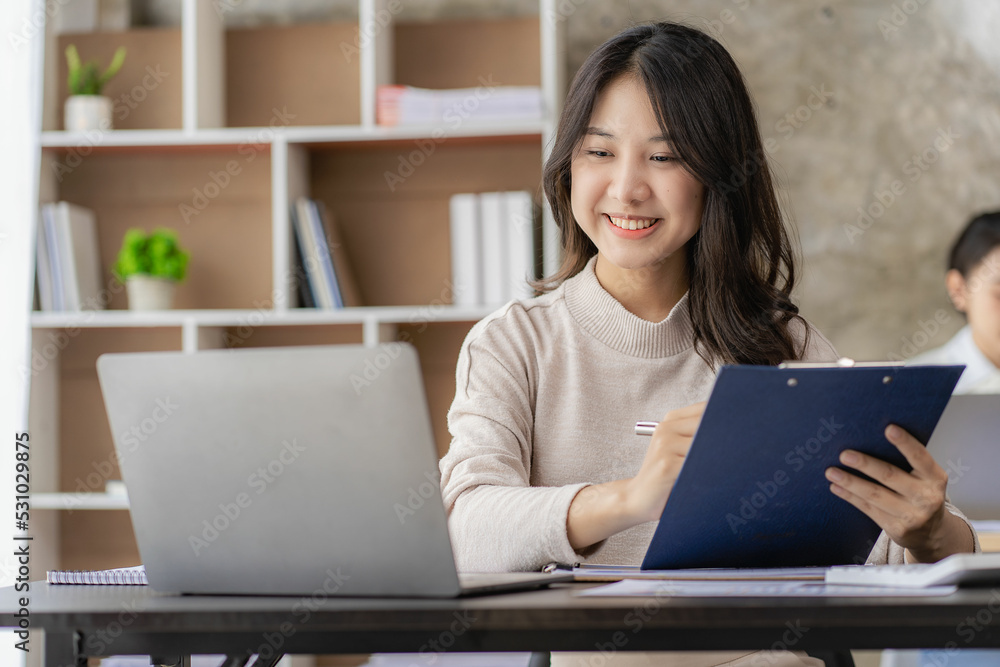 A new generation of Asian female accountants are calculating. Attractive office worker saving, finance and economic concepts to write notepads placed on desktop. A new generation of Asian female accountants are calculating. Attractive office worker saving, finance and economic concepts to write notepads placed on desktop.