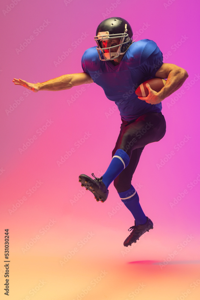 Caucasian male american football player holding ball with neon pink lighting