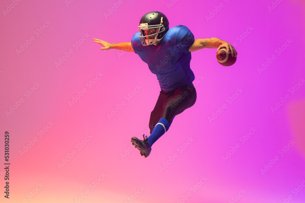 Caucasian male american football player holding ball with neon pink lighting