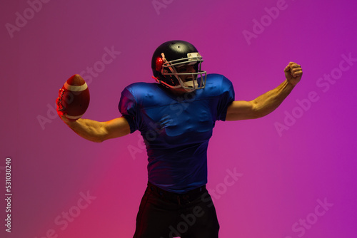 Caucasian male american football player holding ball with neon pink lighting © wavebreak3