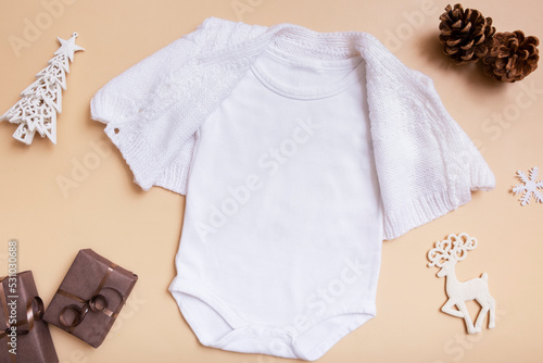 White baby bodysuit mockup for logo, text or design on beige background with winter decotations top view photo