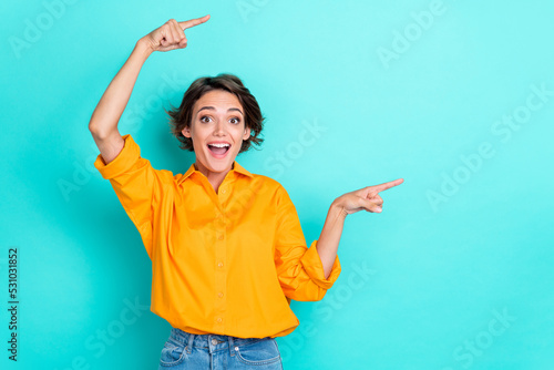 Portrait of ecstatic pretty gorgeous girl wear yellow blouse directing empty space unexpected news isolated on turquoise color background