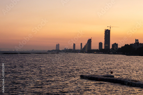 View of the evening city in the foreground of the sea, sunset on the sea