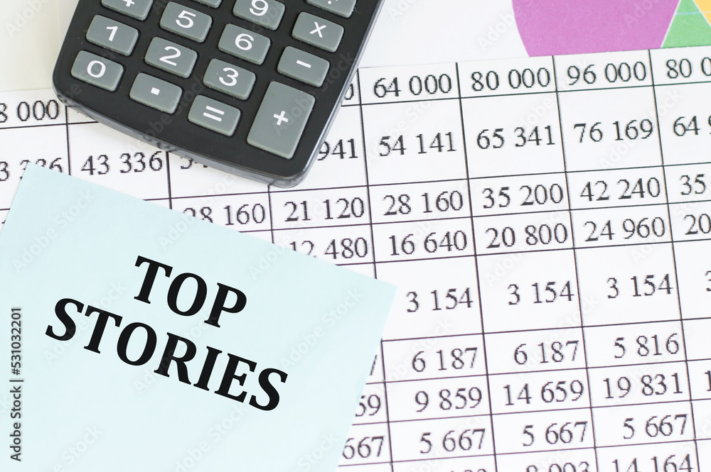TOP STORIES text on a card on the background of documents on the table, business concept TOP STORIES text on a card on the background of documents on the table, business concept