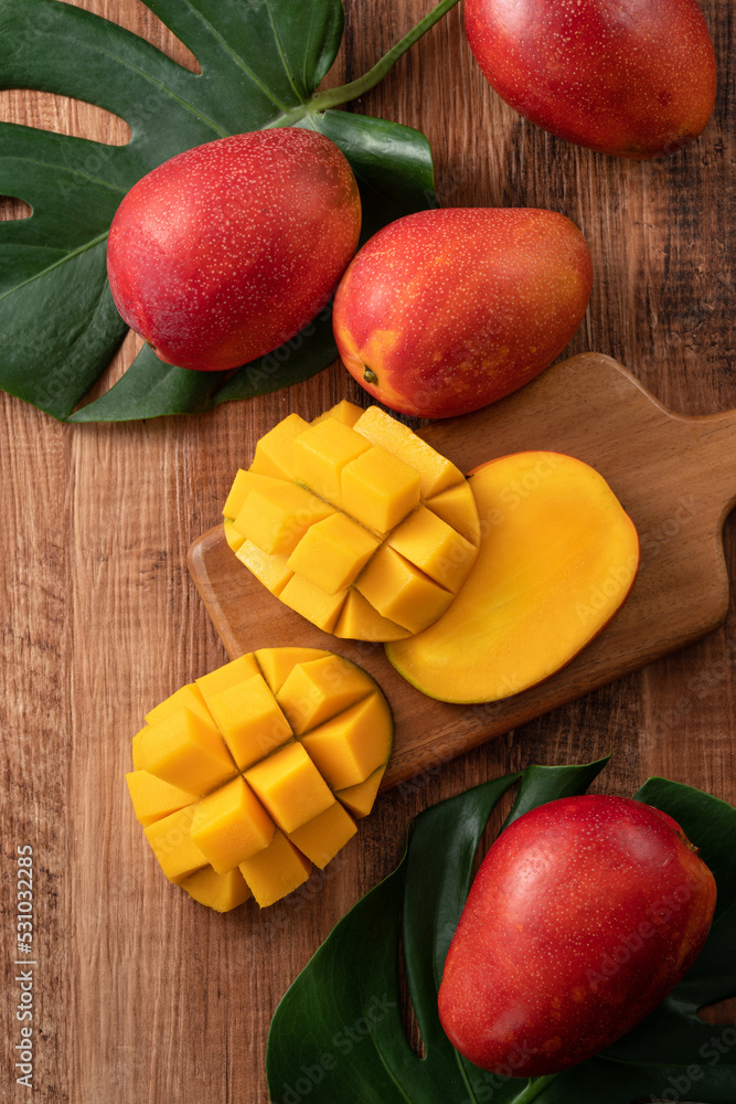 Fresh mango fruit with leaves over dark wooden table background. Fresh mango fruit with leaves over dark wooden table background.