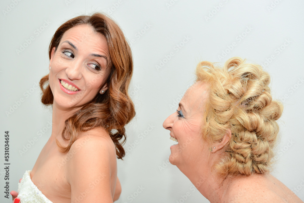 Mother and bride smiling while helping to get dressed on her wedding day. Concept of getting ready in the morning for the wedding day. Mother and bride smiling while helping to get dressed on her wedding day. Concept of getting ready in the morning for the wedding day.