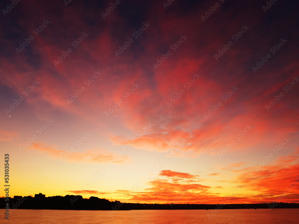 Unique sunset on the shore of the lake with red clouds
