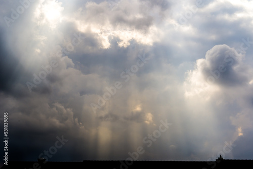 Sun rays and sunlit storm clouds over roof
