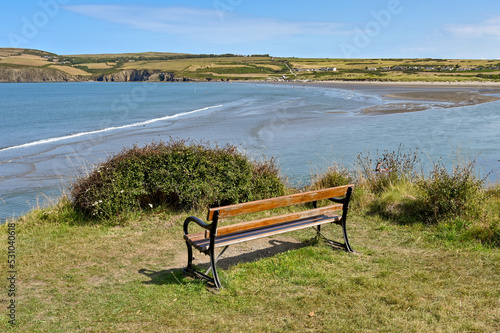 Newport, Pembrokeshire, Wales - August 2022: Wooden bench on the edge of a cliff overlooking Newport Sands