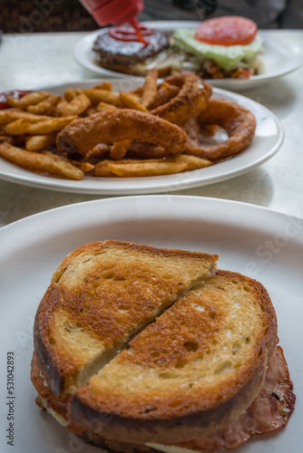 Grilled cheese with ham sandwich on plate in a diner.