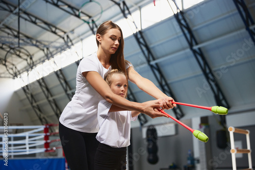 Coaching. Beginner gymnastics athletes doing exercises with gymnastics equipment at sports gym, indoors. Concept of sport, studying, art, education