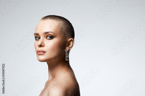 beautiful young woman with short haircut. bald girl with stylish jewelry earrings