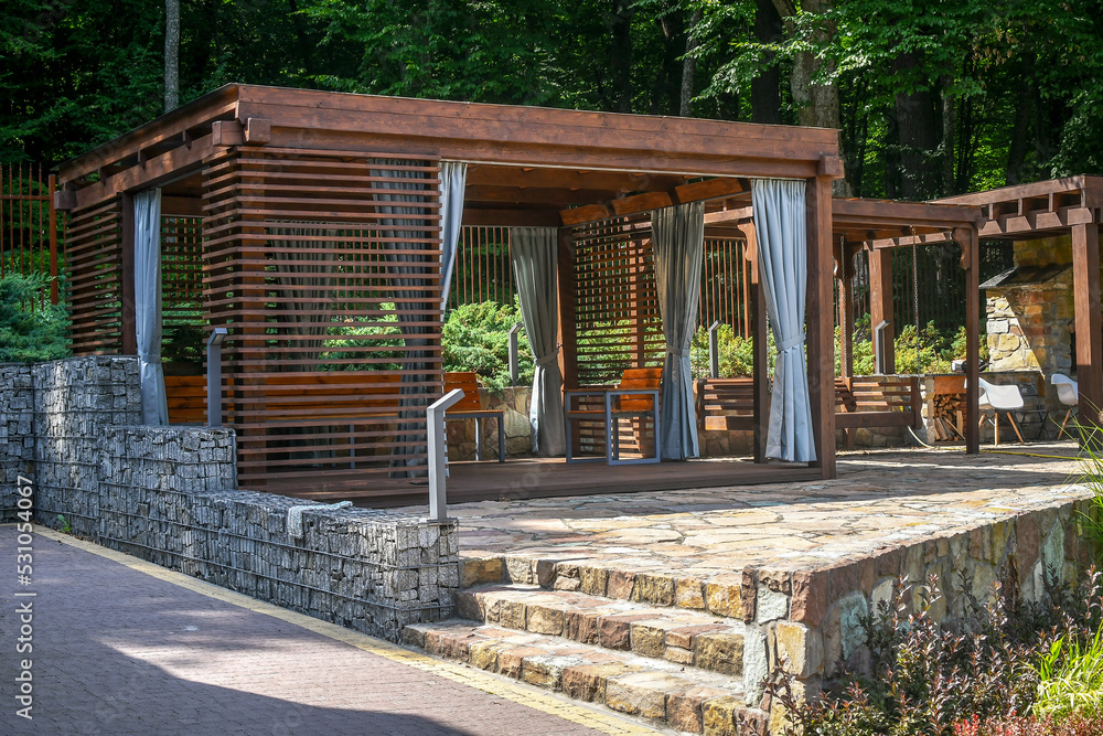 Obraz na plátně Close up wooden gazebo decorated with gabion elements and natural stone pavement