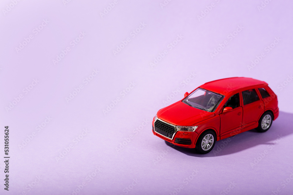 Red children's toy car model isolated on purple background. close up
